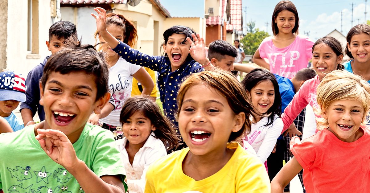 Children in a Roma village in Romania laughing and waving at the camera